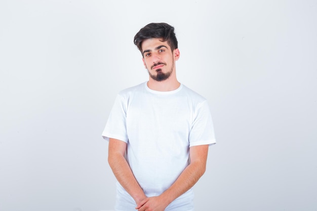 Hombre joven posando mientras está de pie en camiseta y parece seguro