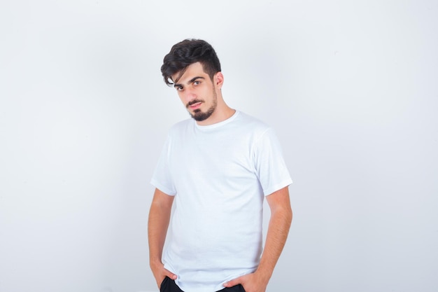 Hombre joven posando mientras está de pie en camiseta y parece seguro