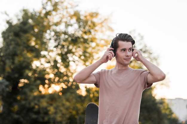 Foto gratuita hombre joven posando con patineta y cascos