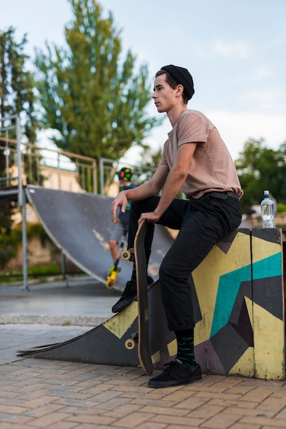 Foto gratuita hombre joven posando con patineta