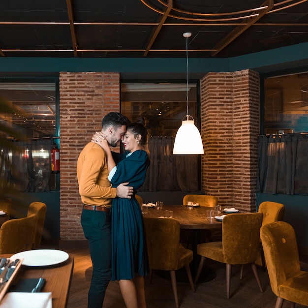 Hombre joven que abraza con la mujer feliz en restaurante