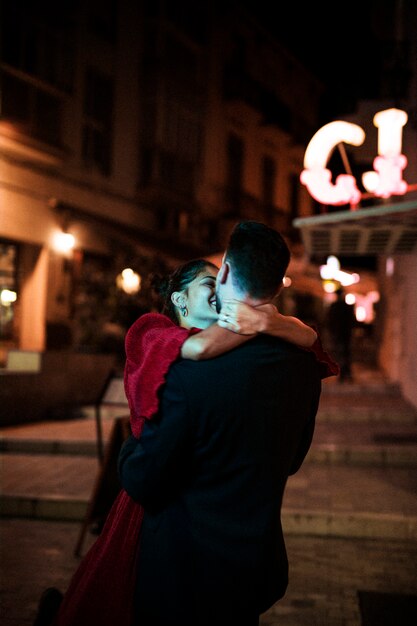 Hombre joven que abraza con la mujer de risa en la calle por la tarde