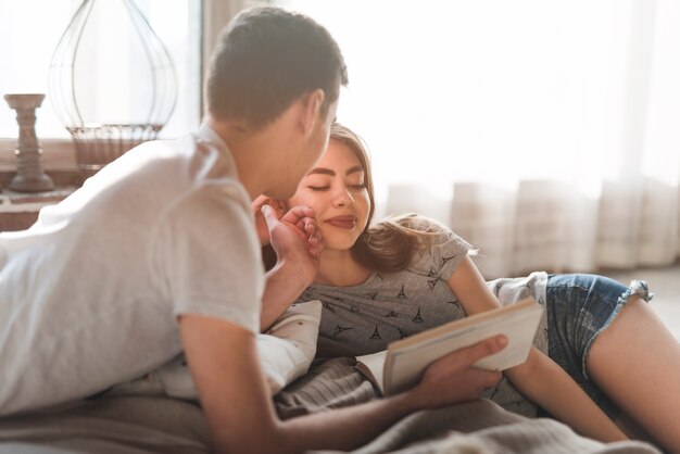 Hombre joven que ama a su novia que miente en cama en casa