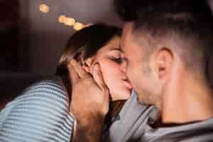 Foto gratuita hombre joven que se besa con la mujer cerca de luces de hadas