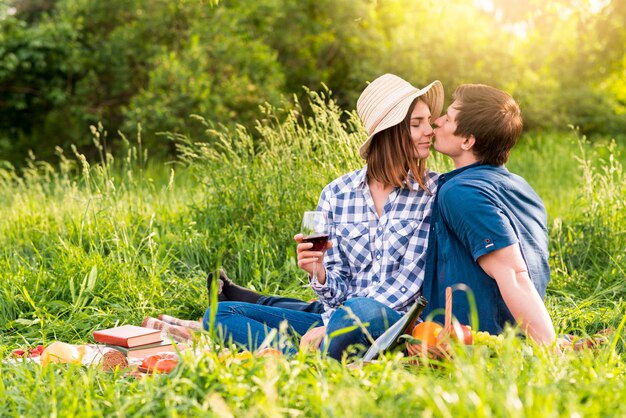 Hombre joven que besa a la mujer en comida campestre