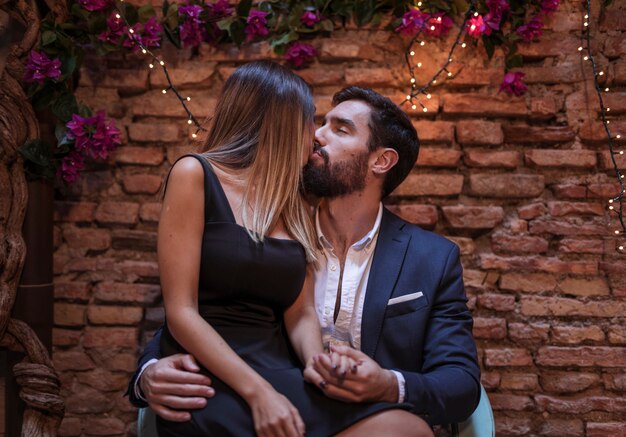 Hombre joven que se besa con la mujer rubia en silla
