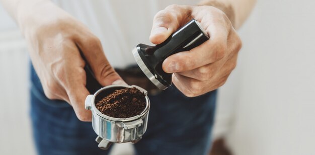 Hombre joven que cocina el café en casa con la cafetera automática. Horizontal. Bandera.