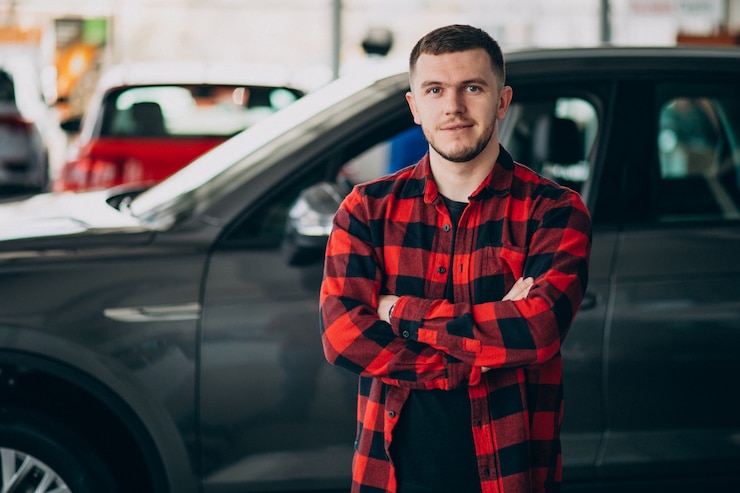 Foto gratuito hombre joven que elige un coche en una sala de exposición de automóviles