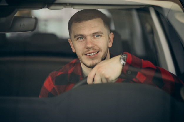 Foto gratuita hombre joven que elige un coche en una sala de exposición de automóviles