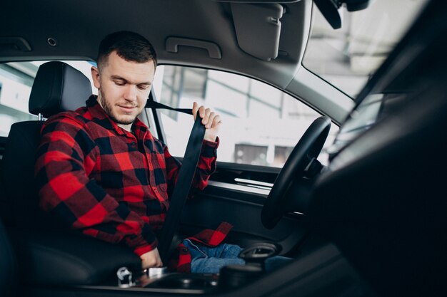 Hombre joven que elige un coche en una sala de exposición de automóviles