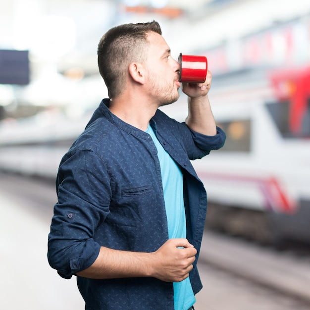 Foto gratuita el hombre joven que llevaba un traje azul. la celebración de una taza roja. mostrando prof