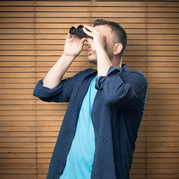 Foto gratuita el hombre joven que llevaba un traje azul. él está usando binoculares