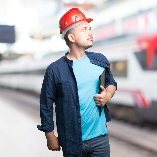 El hombre joven que llevaba un traje azul. El uso de casco rojo. Buscando