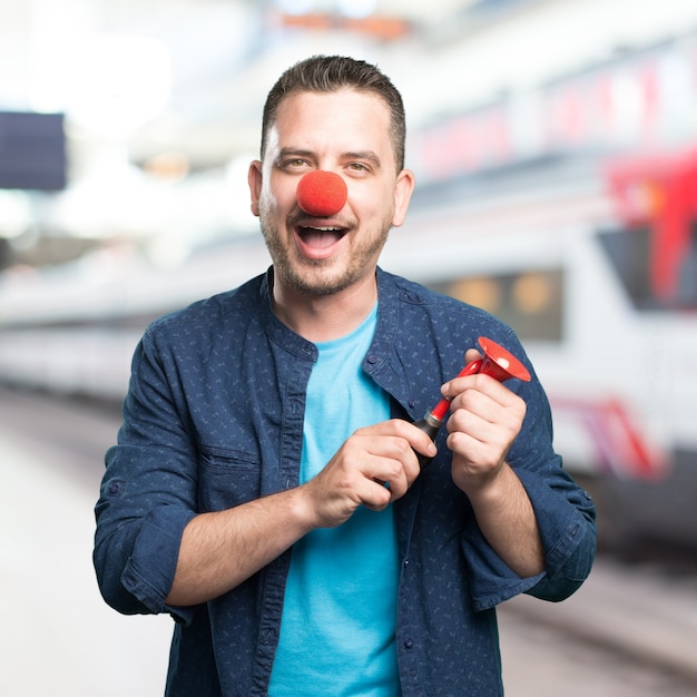 El hombre joven que llevaba un traje azul. El uso de una nariz de payaso. jugar w