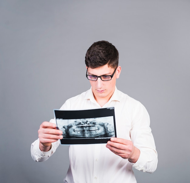 Hombre joven que mira la radiografía de los dientes