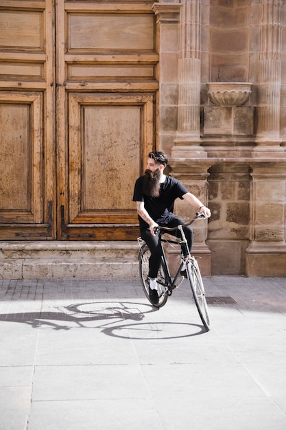 Foto gratuita hombre joven que monta la bicicleta en la calle