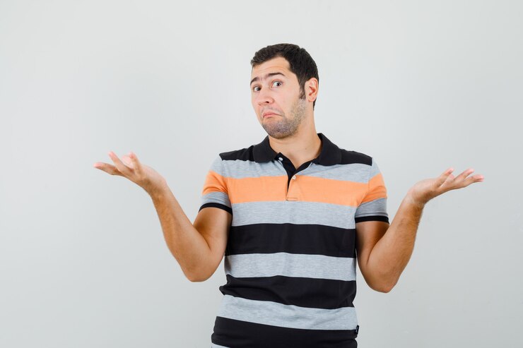 Foto gratuito hombre joven que muestra un gesto de impotencia en camiseta y mirando perplejo, vista frontal.