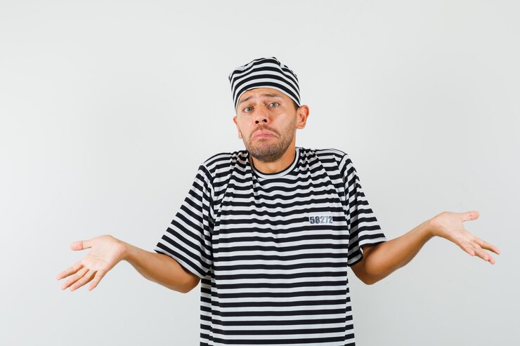 Foto gratuito hombre joven que muestra un gesto de impotencia en camiseta a rayas, sombrero y mirando confundido.