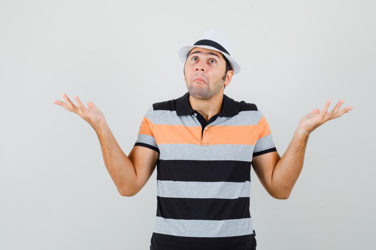 Foto gratuito hombre joven que muestra un gesto de impotencia en camiseta a rayas, sombrero y mirando perplejo, vista frontal.