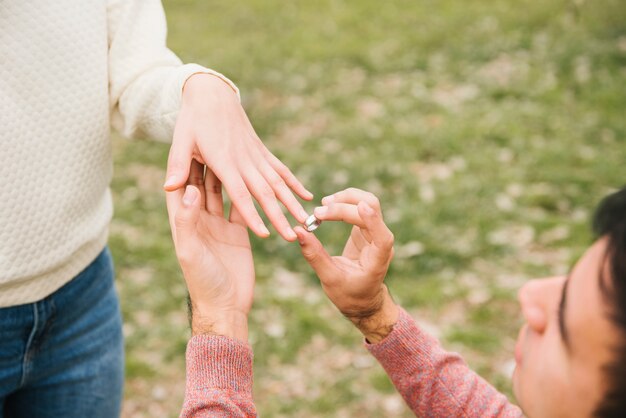 Hombre joven que pone el anillo de bodas en el dedo del amor