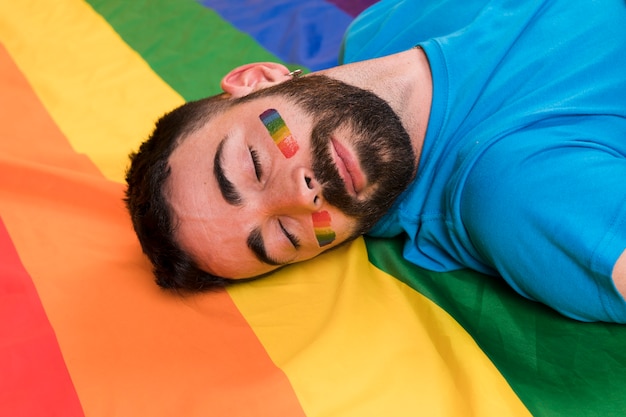 Hombre joven que pone en la bandera de LGBT multicolor