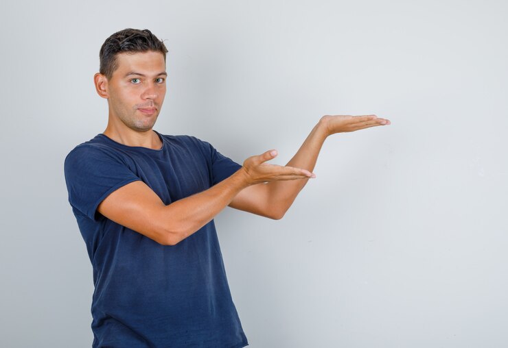 Foto gratuito hombre joven que presenta con palmas en camiseta azul oscuro, vista frontal.