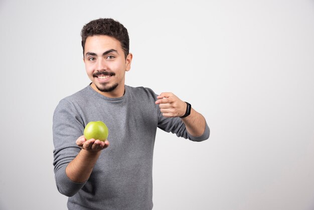 Hombre joven que sostiene la manzana verde en gris.