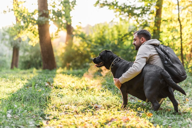 Hombre joven que sostiene su perro de animal doméstico en jardín