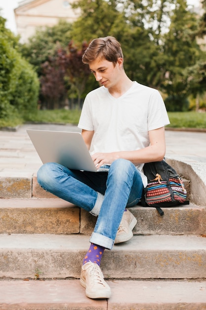 Hombre joven que trabaja en la computadora portátil en el parque