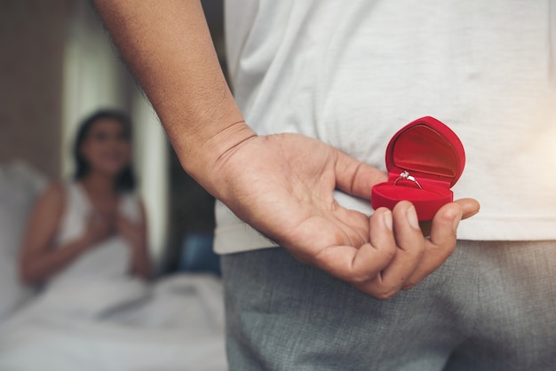 Hombre joven que trae caja de anillo para su novia en su casa