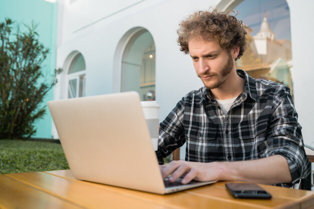 Hombre joven que usa su computadora portátil en una cafetería.