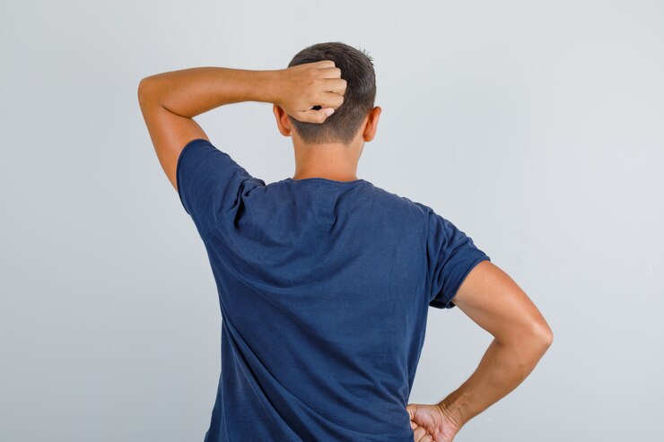 Foto gratuito hombre joven rascándose la cabeza con camiseta azul oscuro, vista posterior.