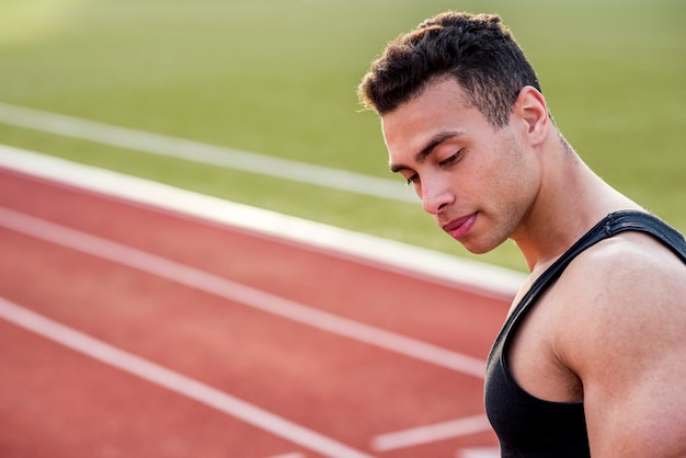 Foto gratuita hombre joven sano en pista que mira lejos