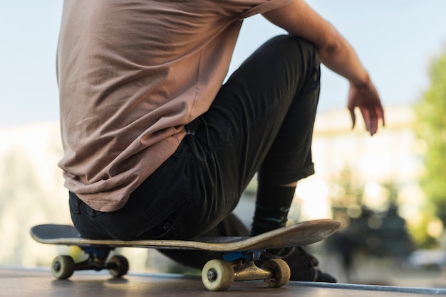 Foto gratuita hombre joven sentado sobre patineta