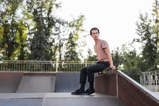 Foto gratuita hombre joven sentado sobre patineta