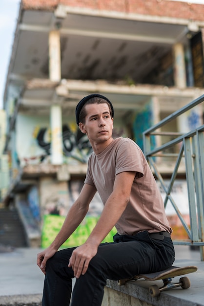 Hombre joven sentado sobre patineta