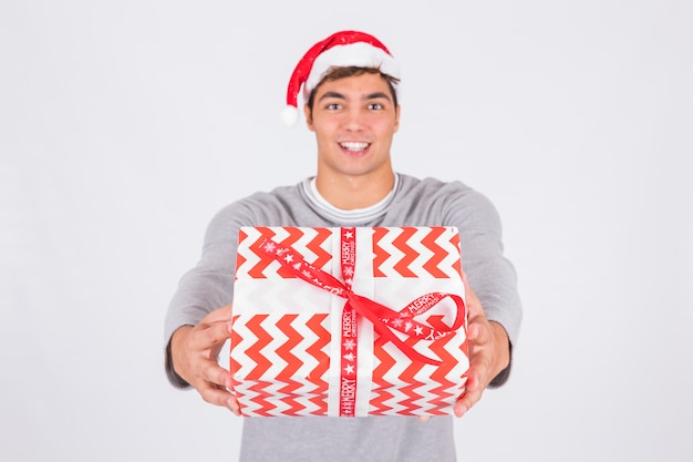 Hombre joven en sombrero de la Navidad con la caja actual en abrigo