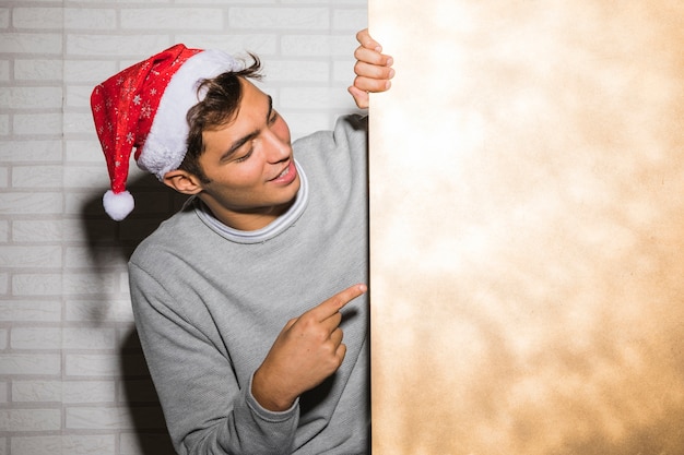 Foto gratuita hombre joven en sombrero de la navidad cerca de la pared