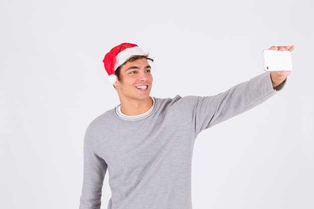 Hombre joven en sombrero de la Navidad con smartphone