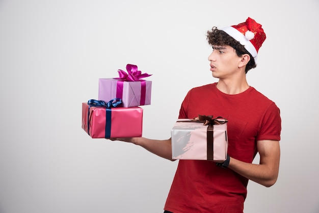 Hombre joven con sombrero de Santa mirando regalos.