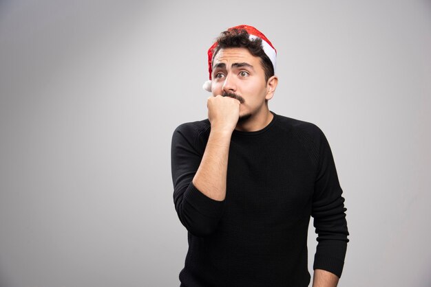 Hombre joven con sombrero de Santa tiene miedo de algo.