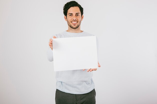 Hombre joven sonriendo con un póster en blanco