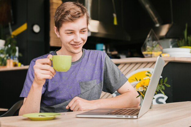 Hombre joven sonriente con la computadora portátil