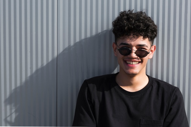 Foto gratuita hombre joven sonriente con las gafas de sol que miran la cámara