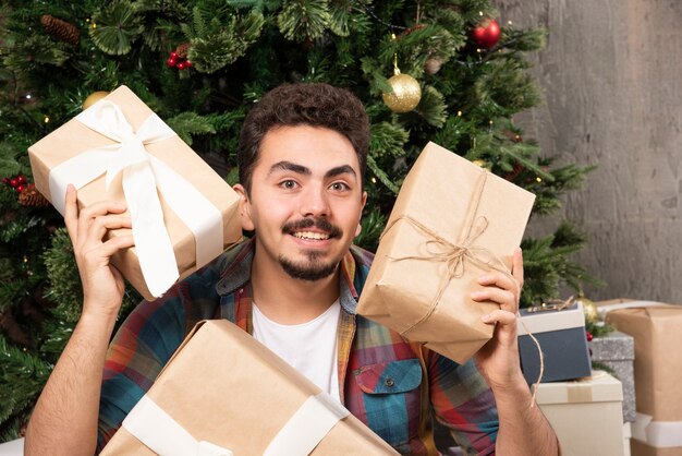 Hombre joven sonriente preguntándose acerca de los regalos.