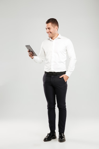 Hombre joven sonriente que charla por la tableta.