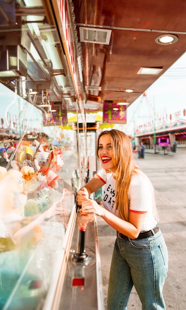 Hombre joven sonriente que juega el juego que ase del juguete en el parque de atracciones