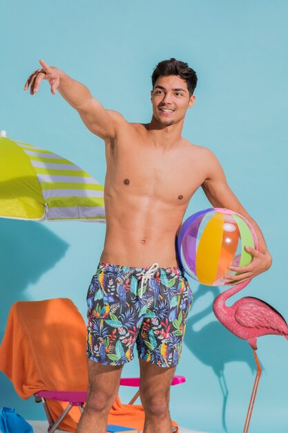 Hombre joven sonriente que muestra lejos en la playa