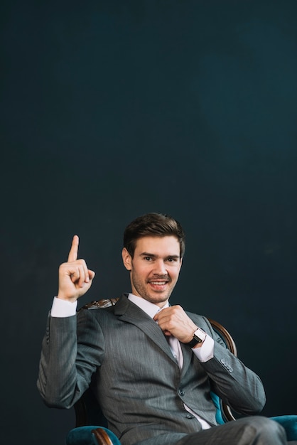 Foto gratuita hombre joven sonriente que señala el dedo hacia arriba contra fondo negro