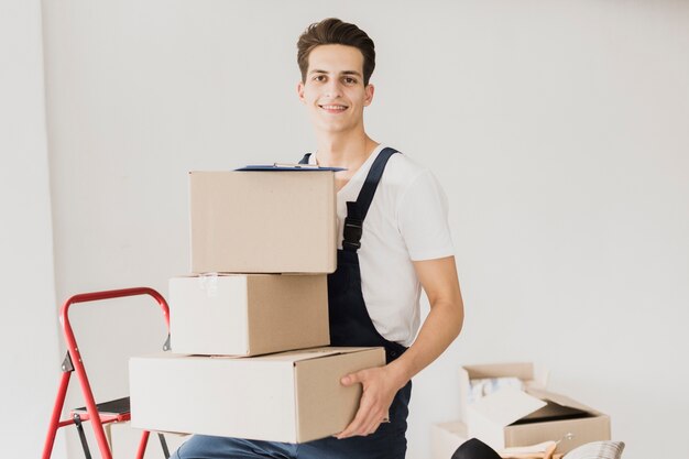 Hombre joven sonriente que sostiene las cajas de cartón